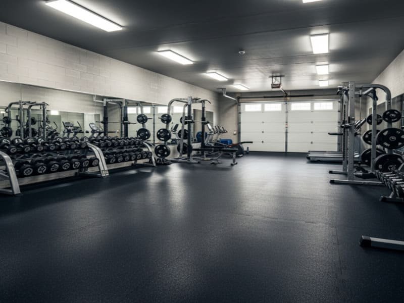 A person easily installing interlocking rubber tiles with a rubber mallet.